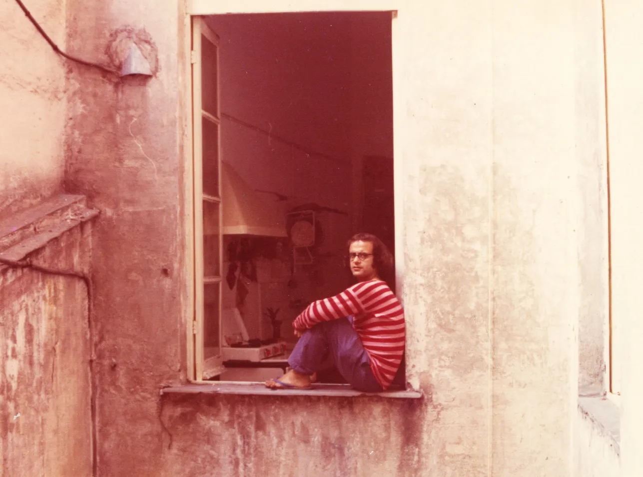 Photograph of the artist dressed as a clown at the window of his studio, Genoa, 1968