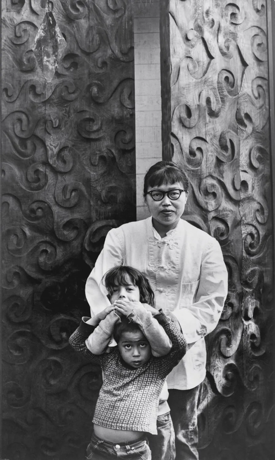 Ruth Asawa with her children Addie and Paul in front of Doors (S.528, Carved Redwood Doors for Ruth Asawa’s Home), at her home in San Francisco, ca. 1965