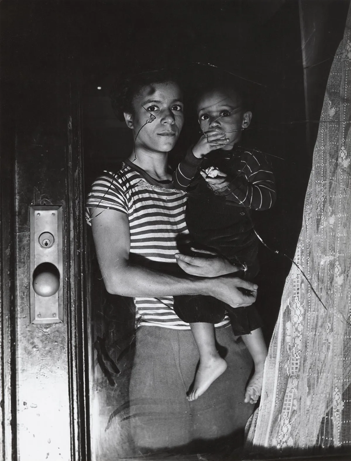Weegee, Mrs. Bernice Lythcott and son looking through window shattered by rock-throwing
hoodlums, Harlem, New York, October 18, 1943